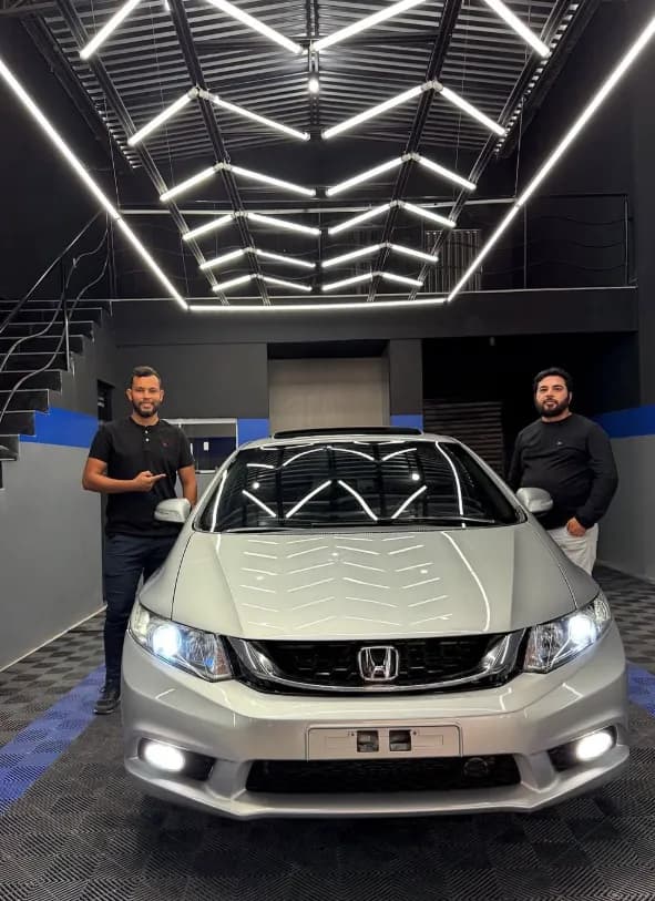 Equipe da Rota do Brilho ao lado de um Honda Civic prata no estúdio